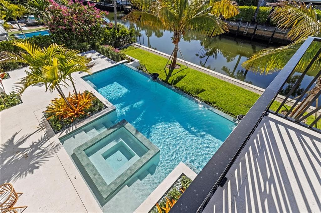 View of pool featuring a pool with connected hot tub, a water view, a yard, and a patio