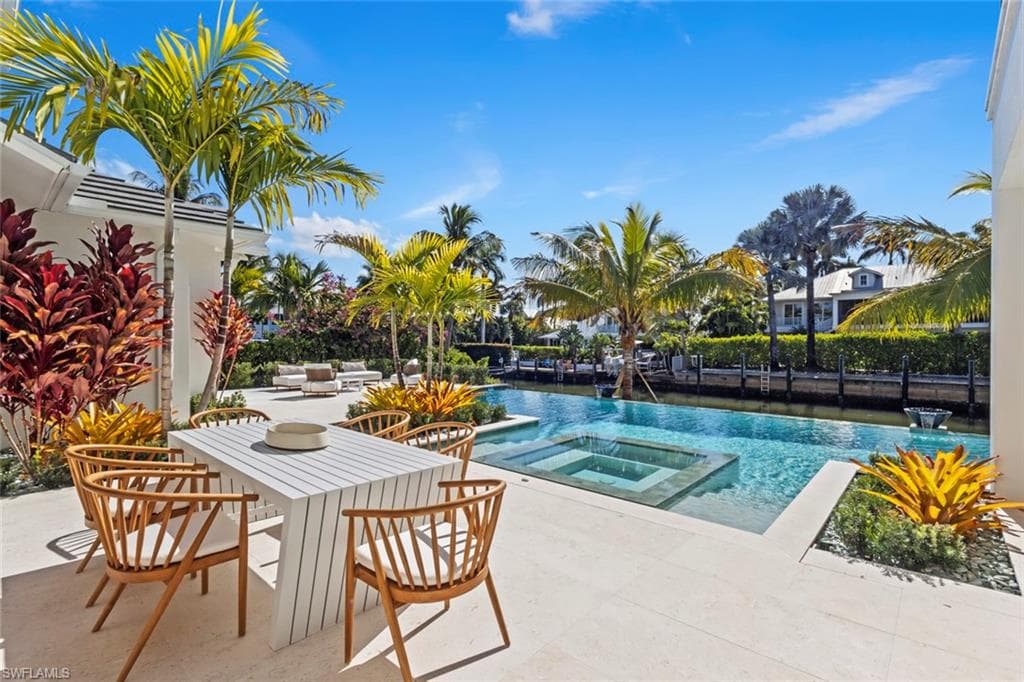 View of swimming pool featuring a patio, a pool with connected hot tub, and outdoor dining area