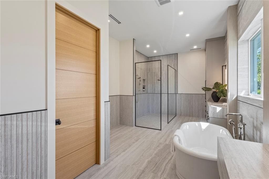 Full bath featuring wainscoting, a shower stall, recessed lighting, a freestanding bath, and vanity