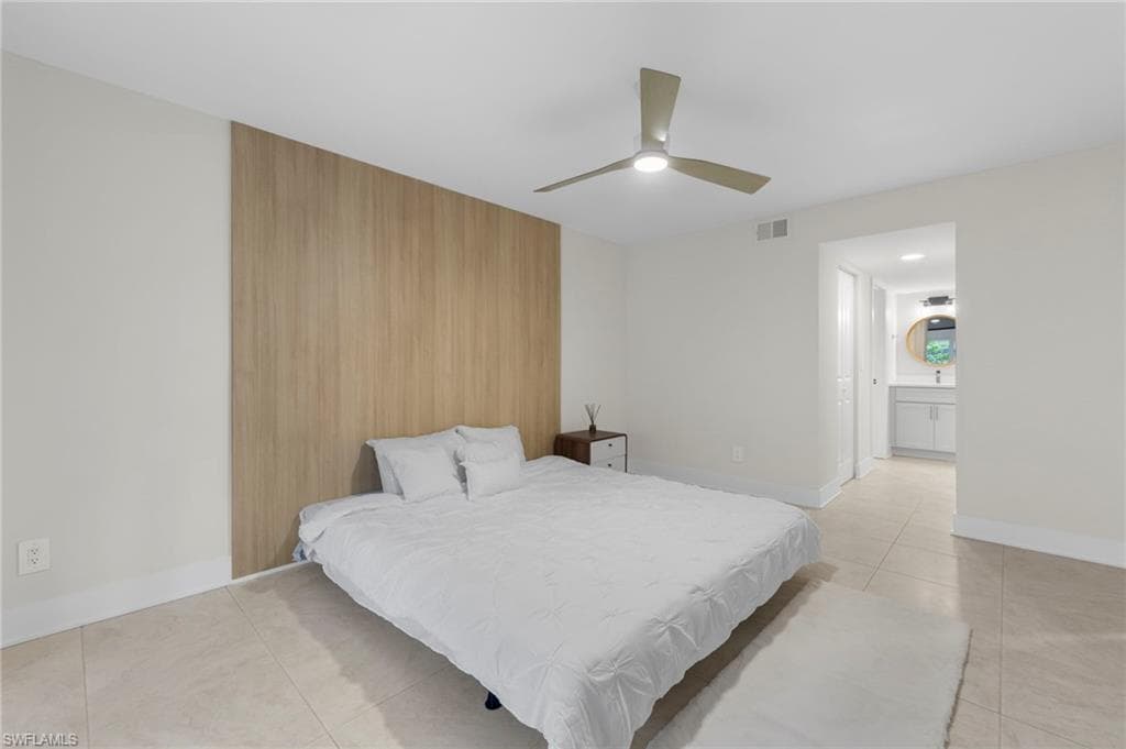 Tiled bedroom featuring ensuite bath and ceiling fan