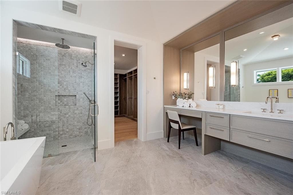 Full bath with a spacious closet, visible vents, vanity, a freestanding tub, and a stall shower