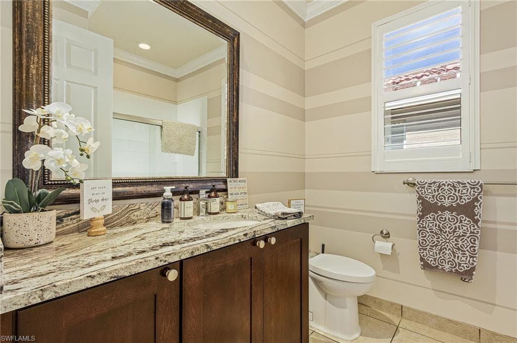 Bathroom with tile floors, ornamental molding, vanity, and toilet
