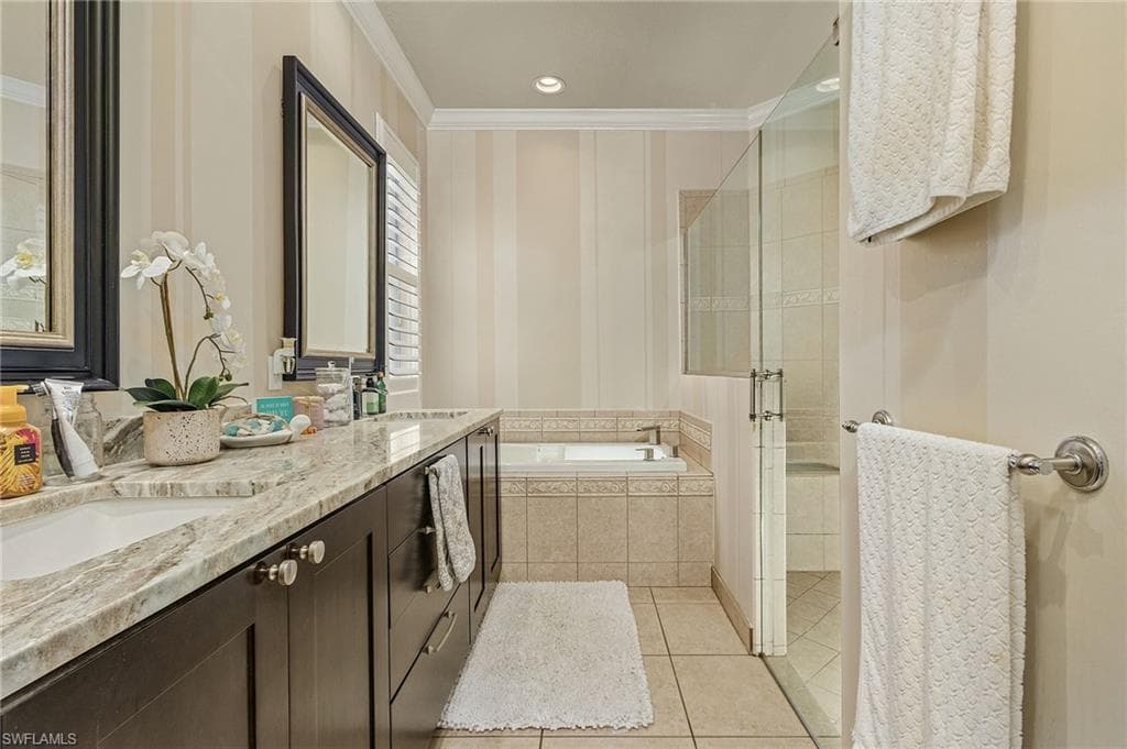 Bathroom featuring tile floors, ornamental molding, separate shower and tub, and double vanity