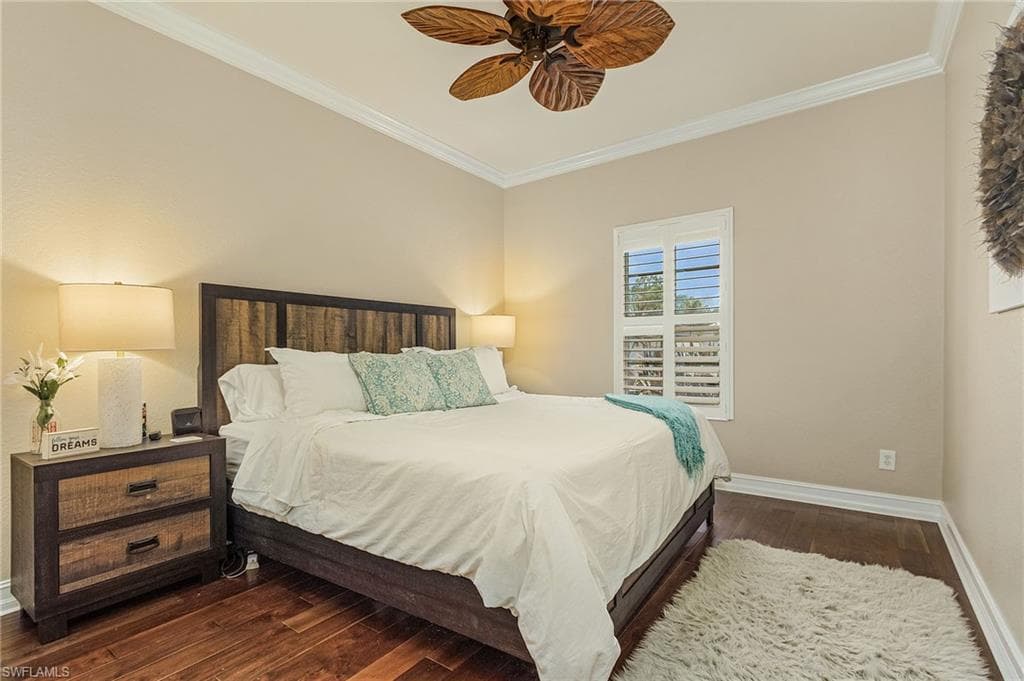 Bedroom featuring dark wood-type flooring, ceiling fan, and crown molding