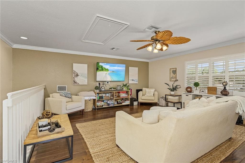 Living room with dark hardwood / wood-style flooring, ceiling fan, and crown molding