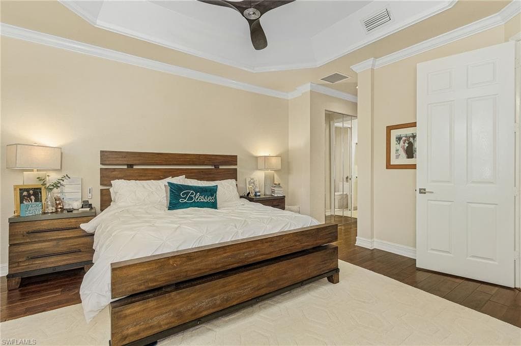 Bedroom with ceiling fan, a tray ceiling, and hardwood / wood-style floors