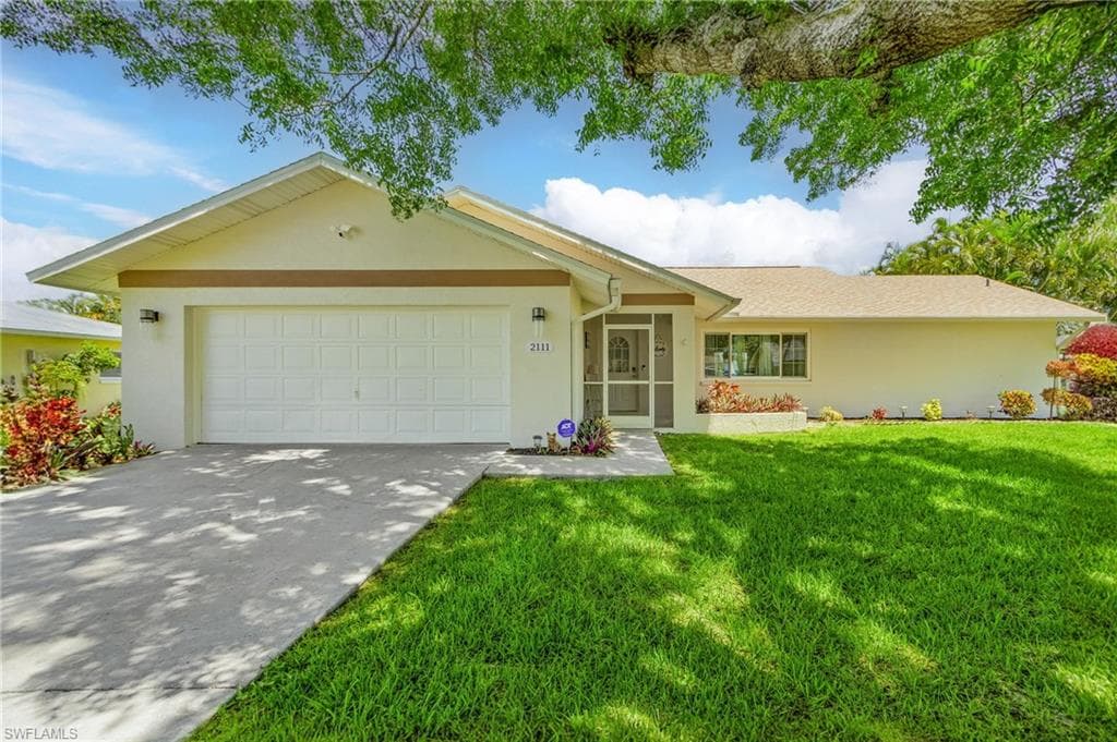 Ranch-style house featuring a garage and a front yard