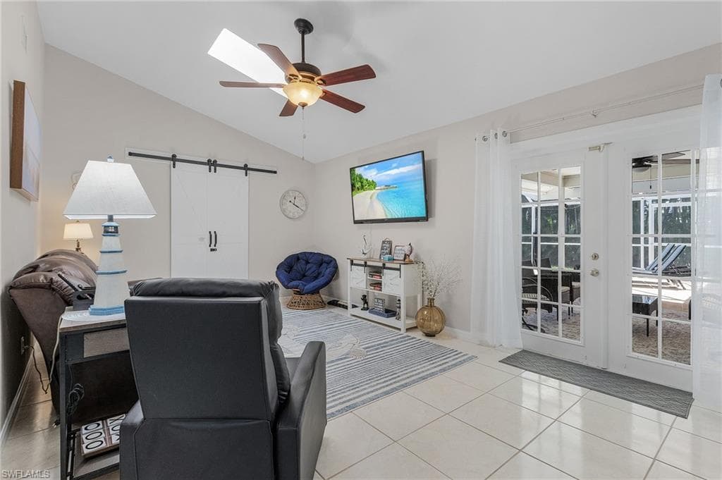 Living room featuring plenty of natural light, light tile flooring, ceiling fan, and vaulted ceiling