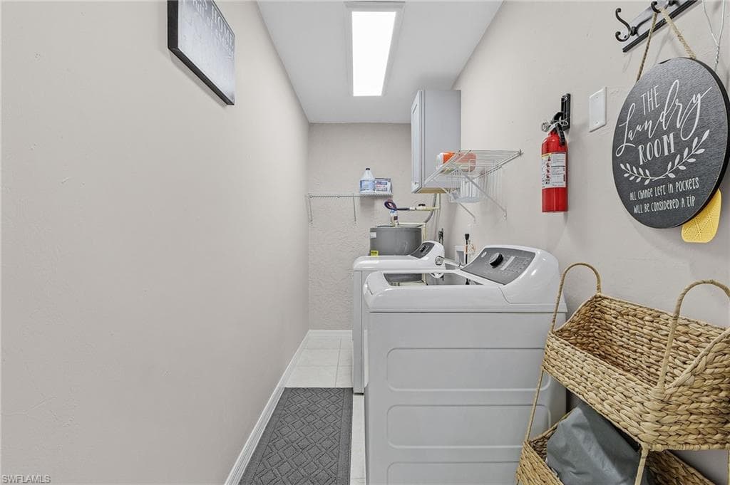 Washroom with water heater, tile floors, and washing machine and clothes dryer