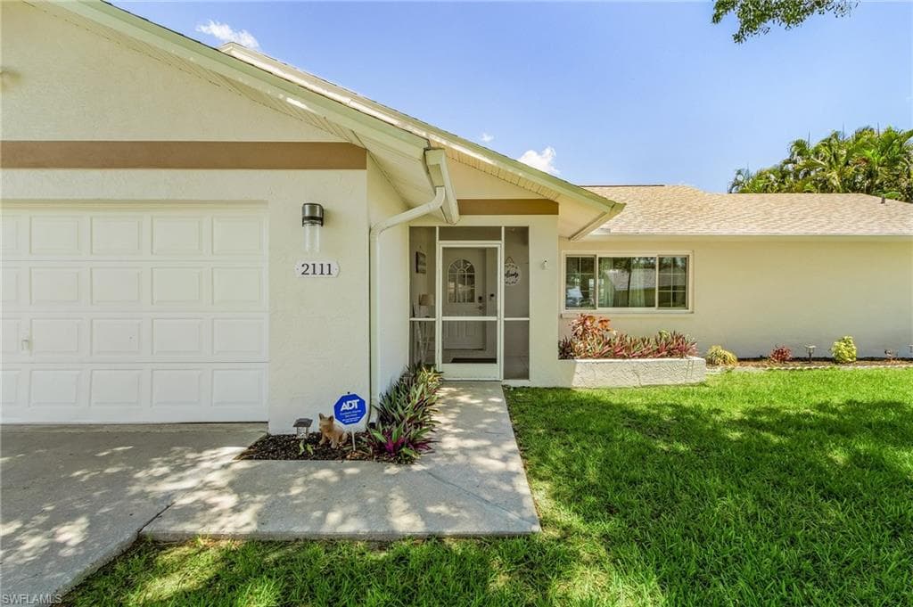 View of exterior entry featuring a garage and a yard