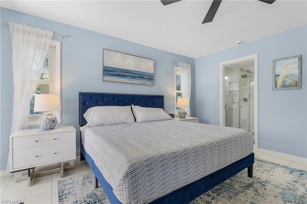 Bedroom featuring ceiling fan, ensuite bathroom, and light tile floors