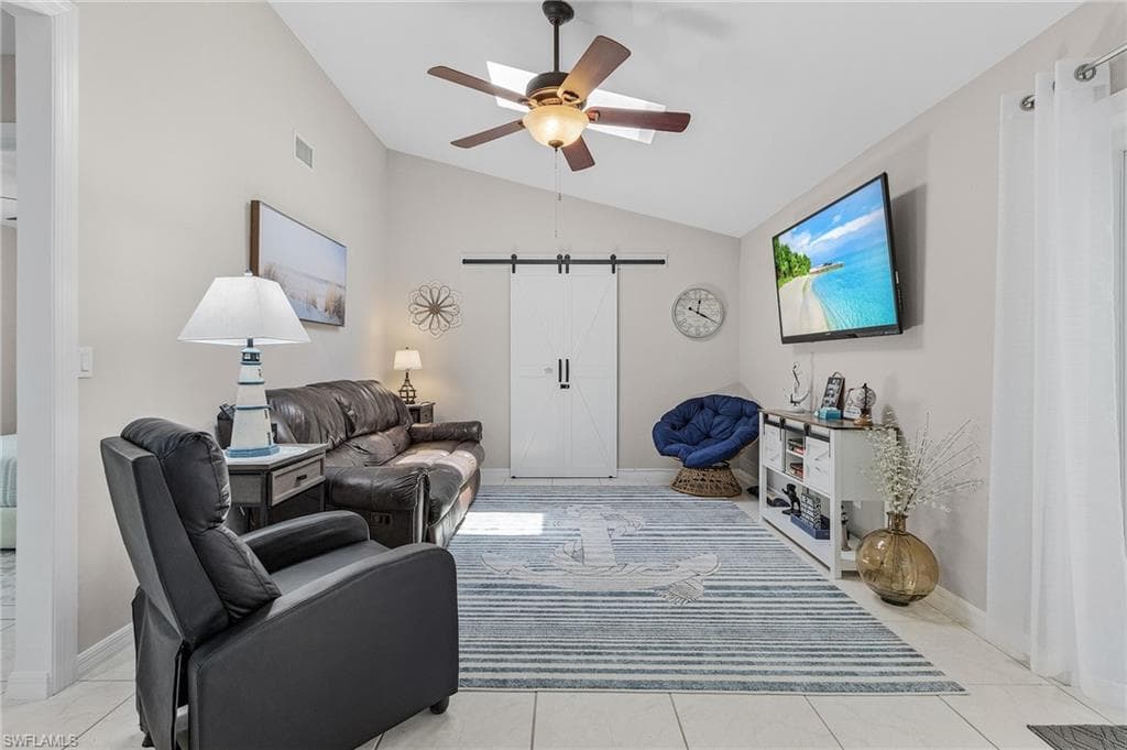 Living room with ceiling fan, light tile floors, and lofted ceiling