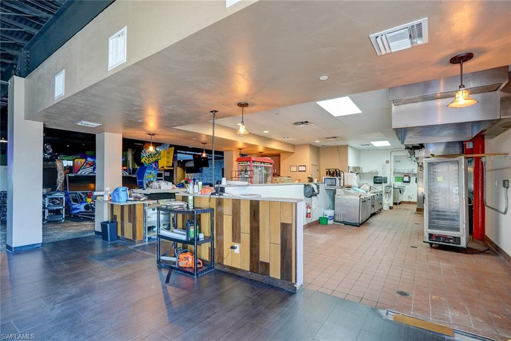 Kitchen with hanging light fixtures, tile flooring, a center island, and kitchen peninsula