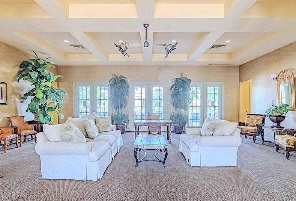 Living room with coffered ceiling, beam ceiling, plenty of natural light, and carpet