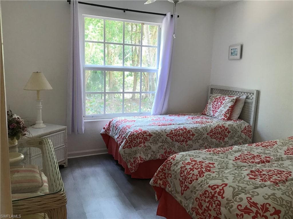 Bedroom featuring ceiling fan, dark hardwood / wood-style floors, and multiple windows