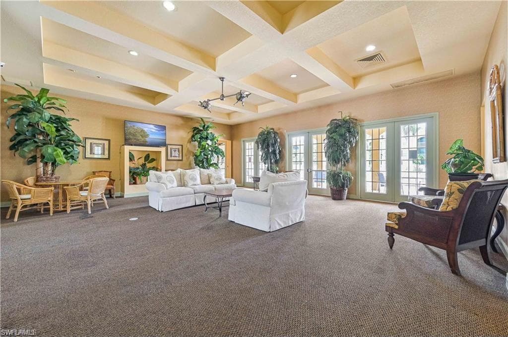Carpeted living room with coffered ceiling, beam ceiling, and french doors