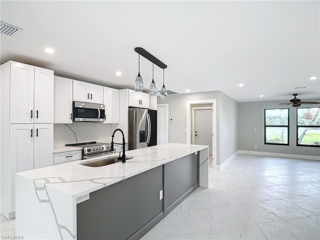 Kitchen featuring decorative light fixtures, appliances with stainless steel finishes, ceiling fan, and white cabinets