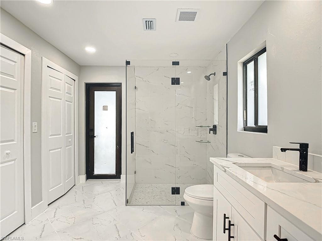 Bathroom with a shower with shower door, vanity, toilet, and tile floors
