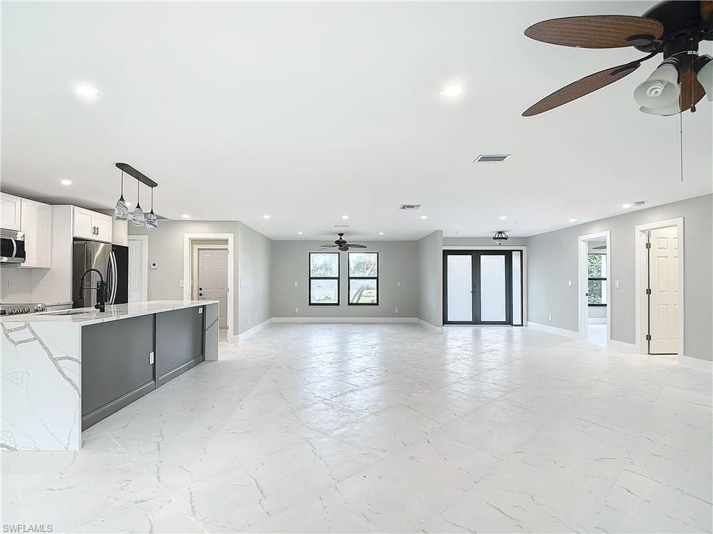 Unfurnished living room featuring sink, ceiling fan, and light tile floors