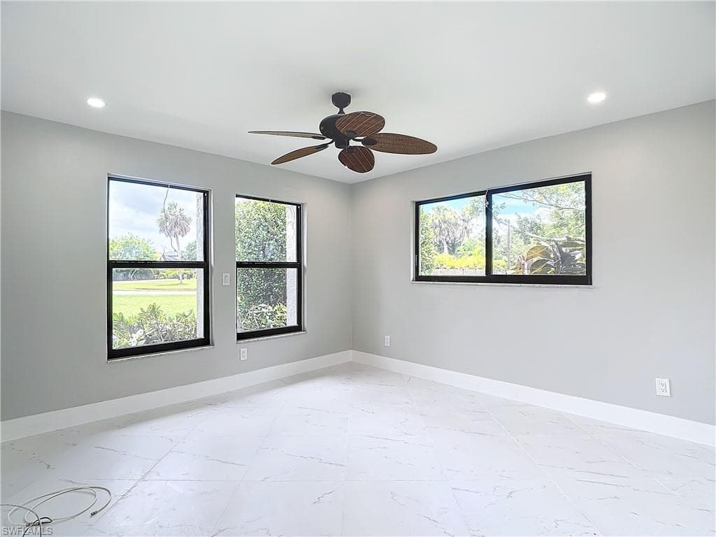 Empty room with ceiling fan and light tile flooring