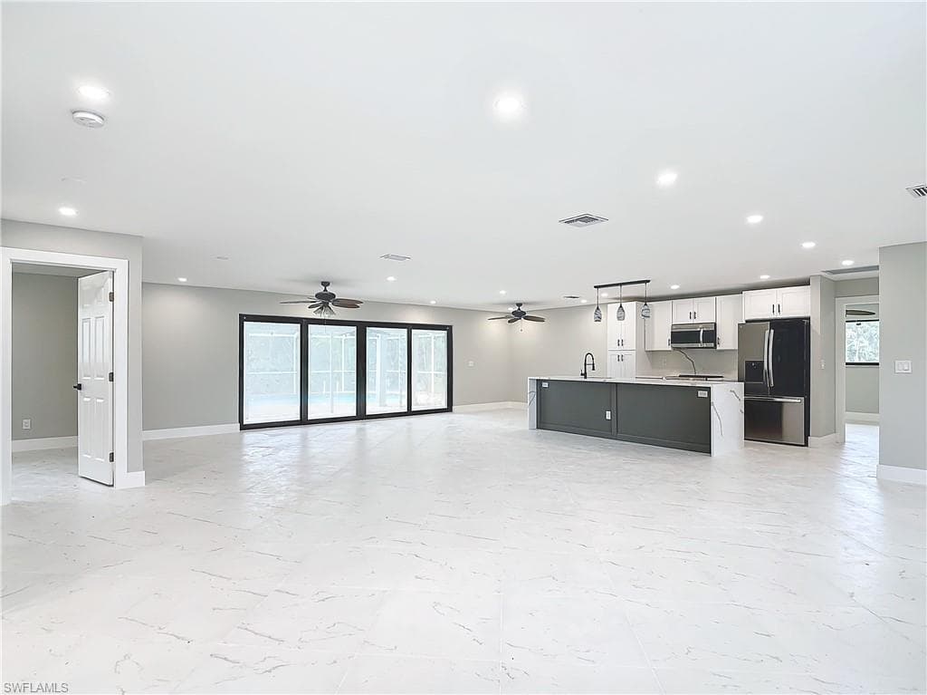 Unfurnished living room with sink, light tile flooring, and ceiling fan