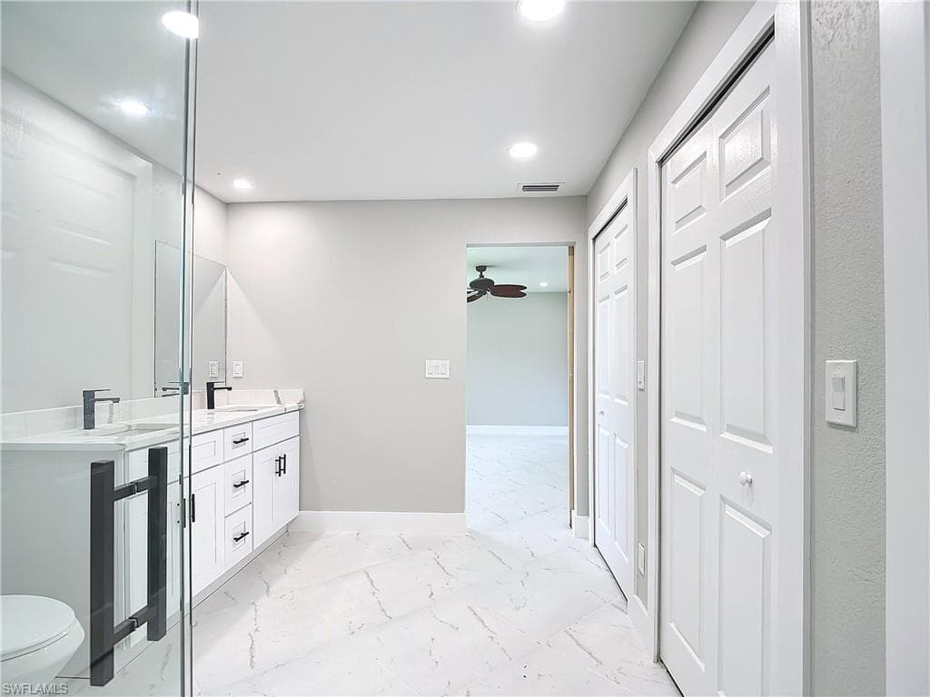 Bathroom with tile floors, ceiling fan, double vanity, and toilet