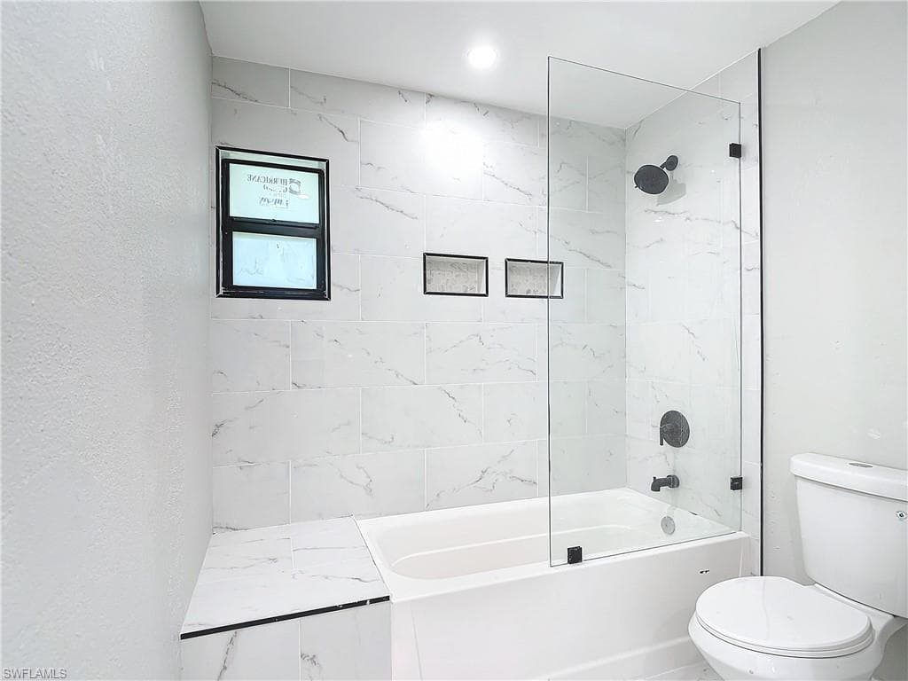 Bathroom with tiled shower / bath and toilet