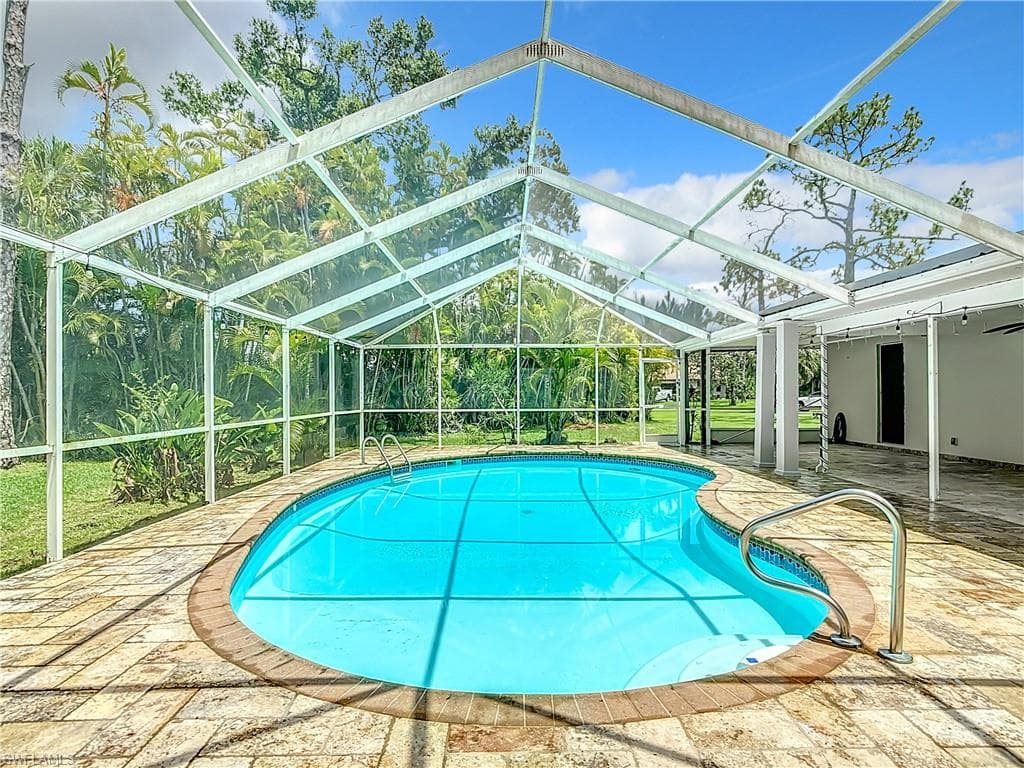View of pool with a patio and glass enclosure