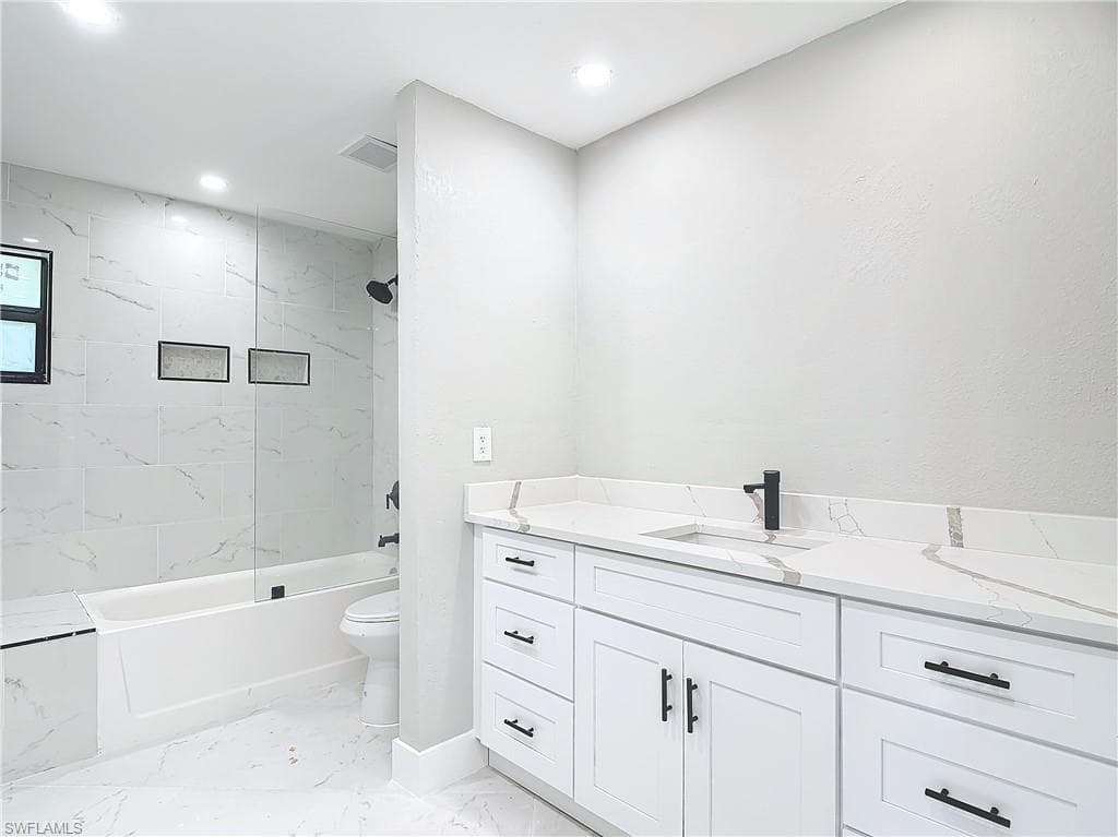 Full bathroom featuring tile floors, tiled shower / bath combo, vanity, and toilet