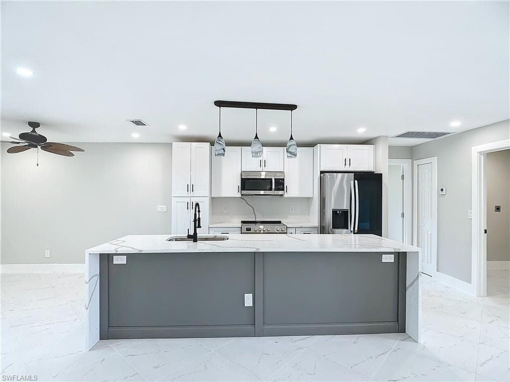 Kitchen featuring a center island with sink, appliances with stainless steel finishes, and light tile floors