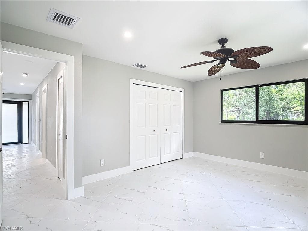 Unfurnished bedroom with a closet, ceiling fan, and light tile floors