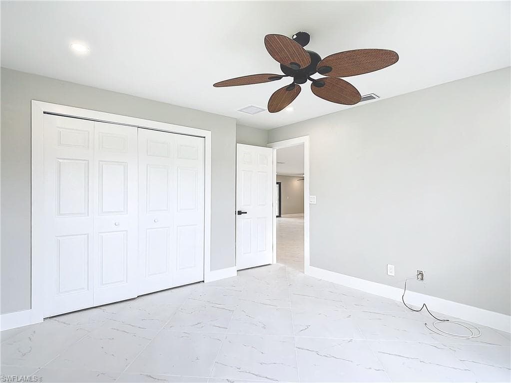 Unfurnished bedroom with a closet, light tile flooring, and ceiling fan