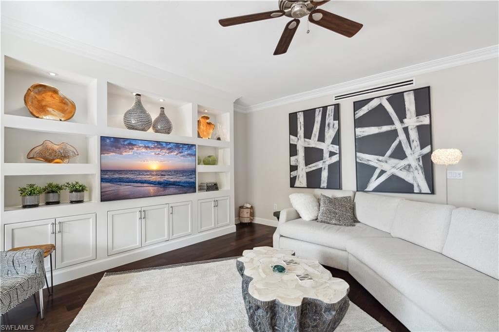 Living room featuring built in features, ceiling fan, dark hardwood / wood-style flooring, and ornamental molding