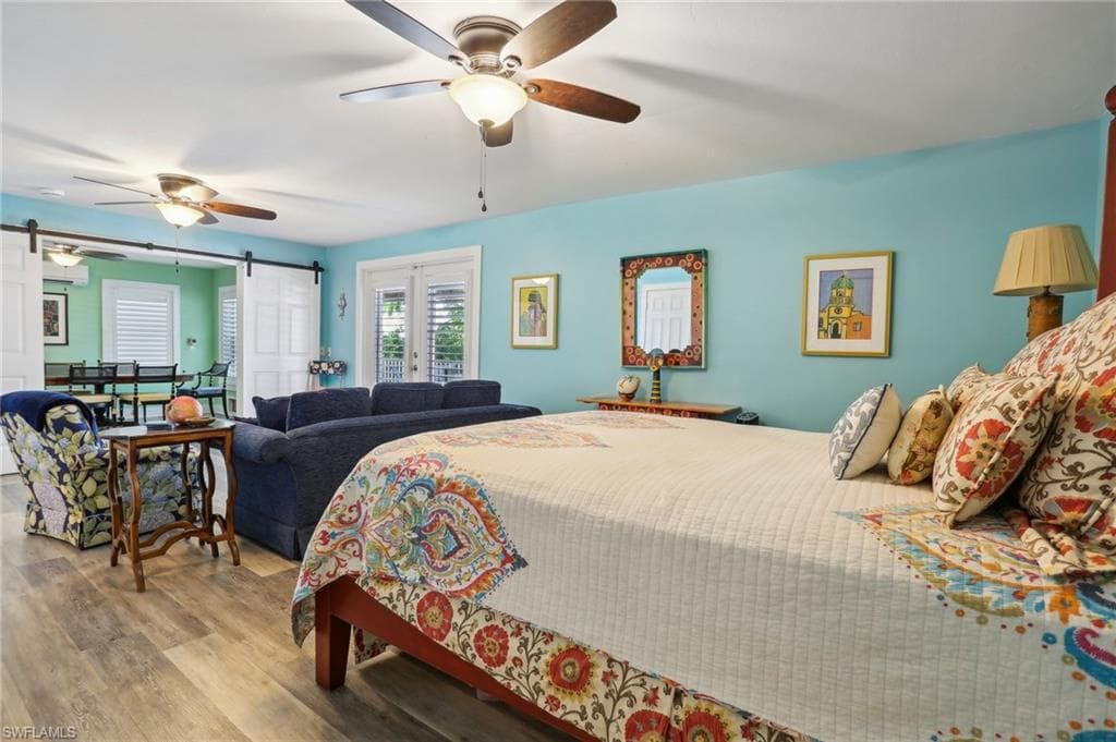 Bedroom featuring ceiling fan, light hardwood / wood-style flooring, and a barn door