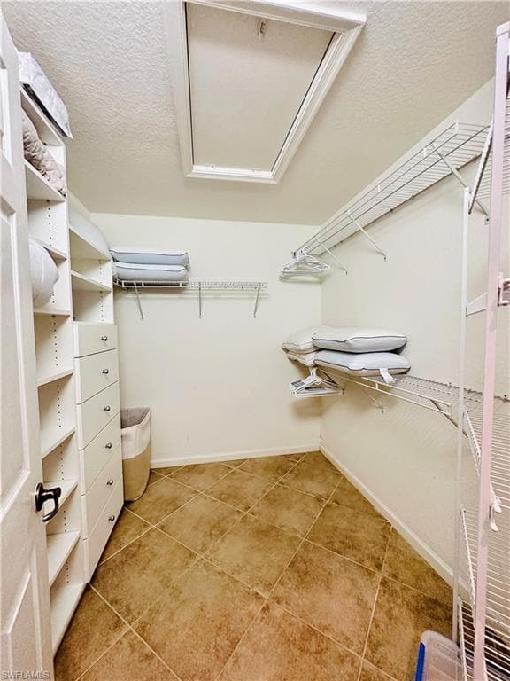 Walk in master closet featuring light tile patterned flooring