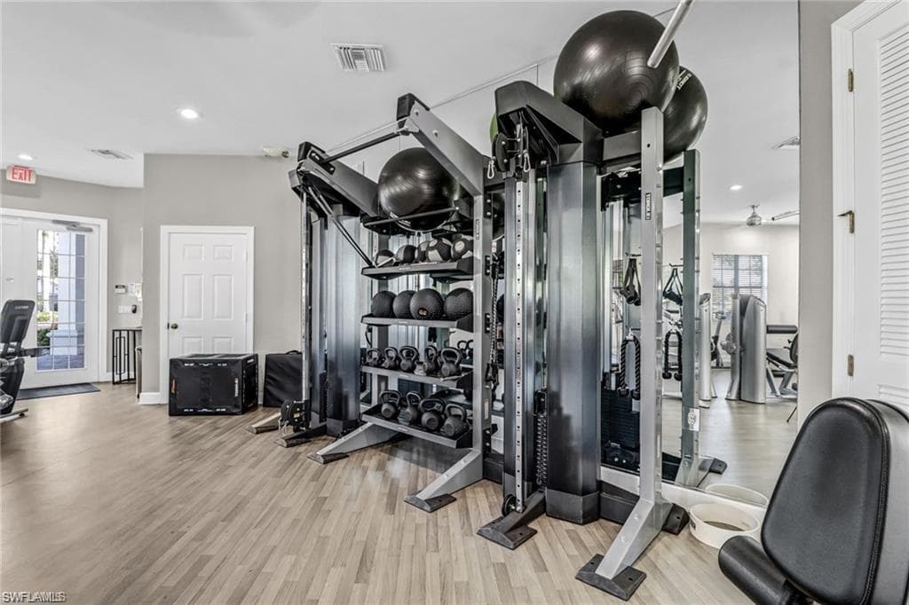 Workout area with french doors and light wood-type flooring