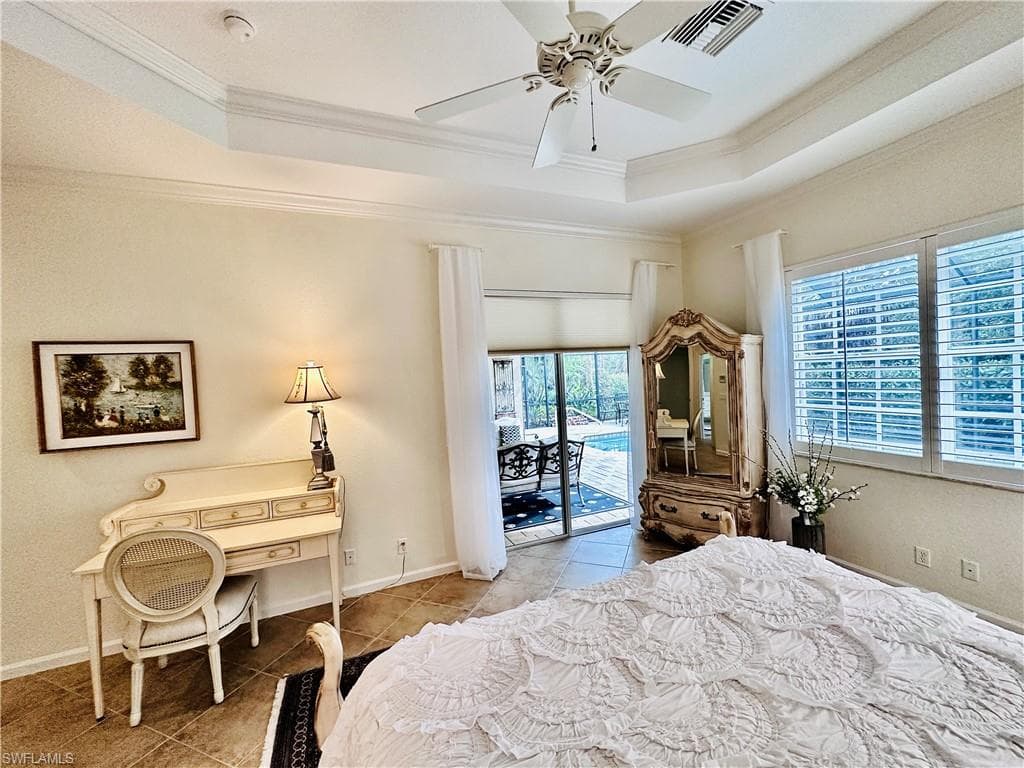 Bedroom with a raised ceiling, access to outside, light tile patterned floors, and ceiling fan