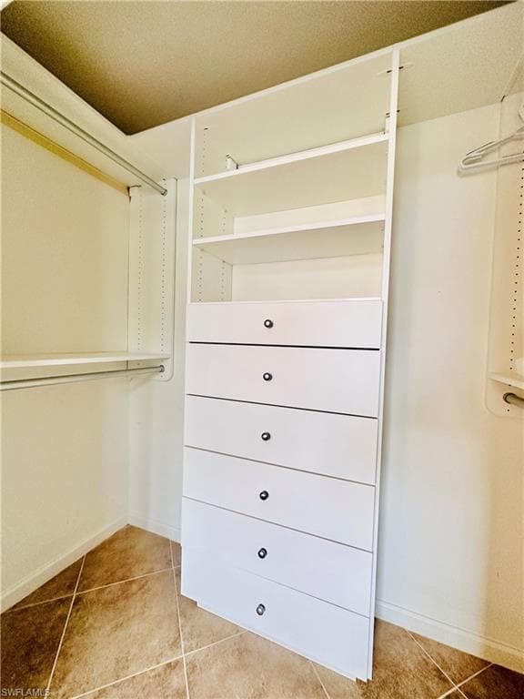 Spacious master closet with light tile patterned floors