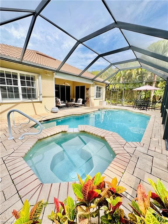 View of swimming pool with an in ground hot tub, a patio, and a lanai