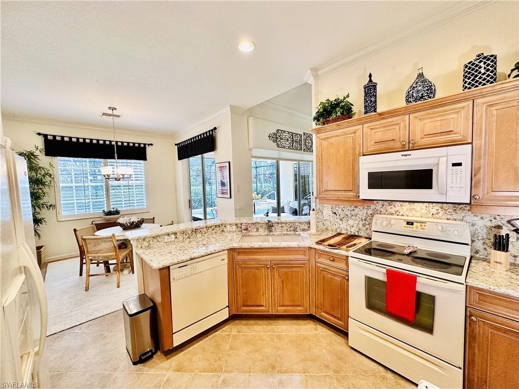Kitchen featuring light tile patterned floors, a wealth of natural light, tasteful backsplash, and white appliances