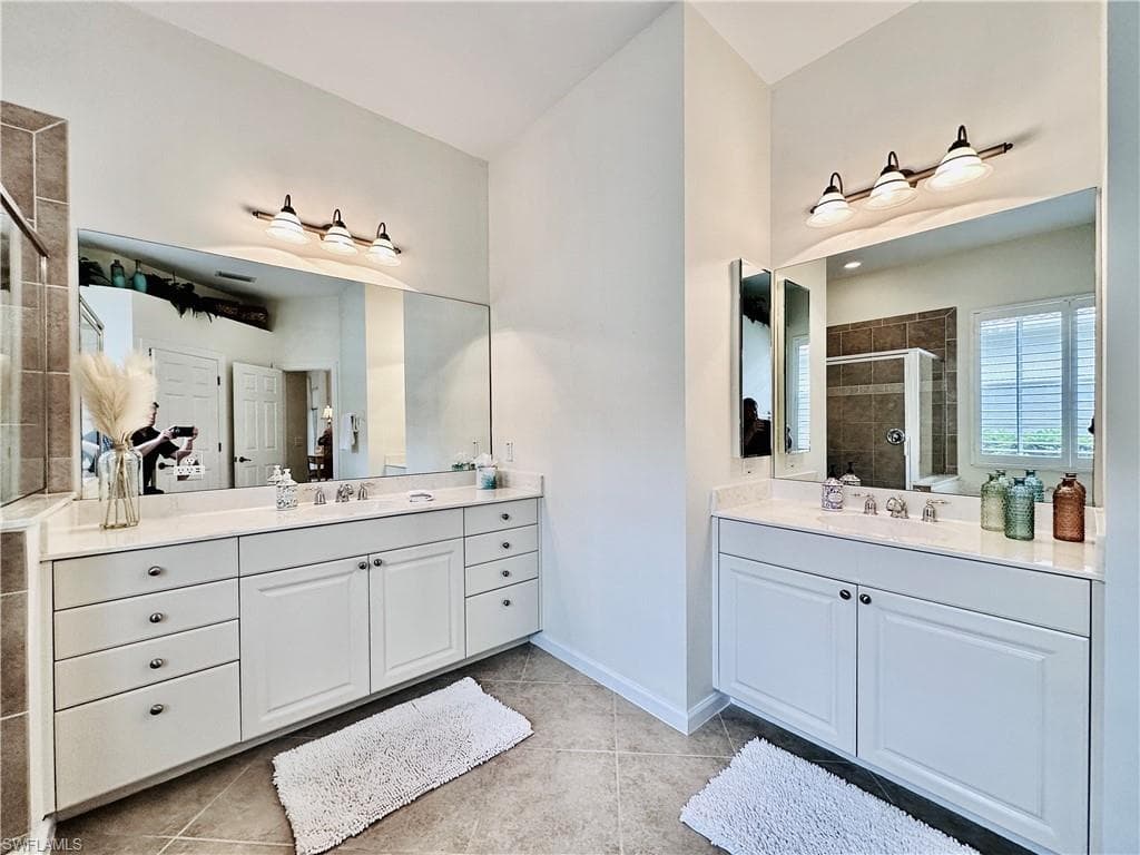 Bathroom featuring tile patterned flooring, walk in shower, and vanity