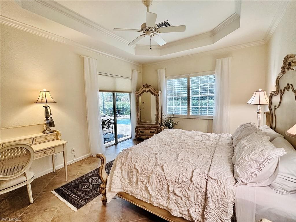 Tiled bedroom with a raised ceiling, access to outside, ornamental molding, and ceiling fan