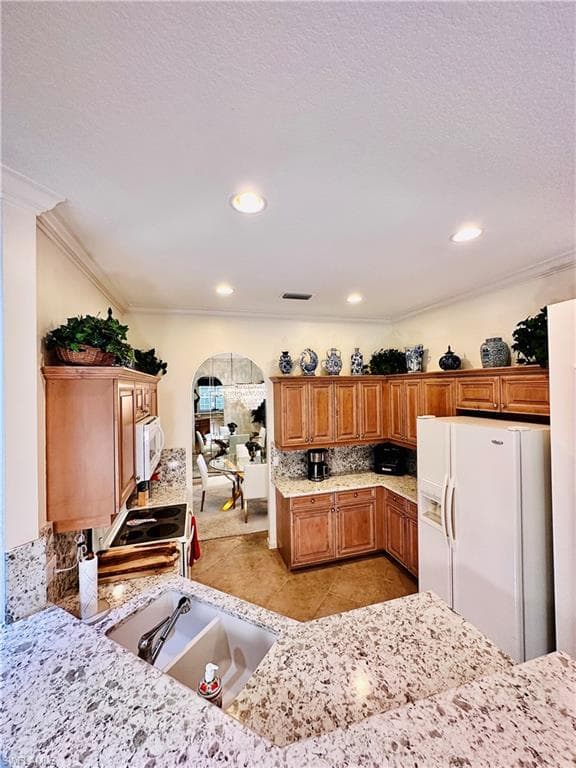 Kitchen with light tile patterned flooring, sink, white appliances, and ornamental molding