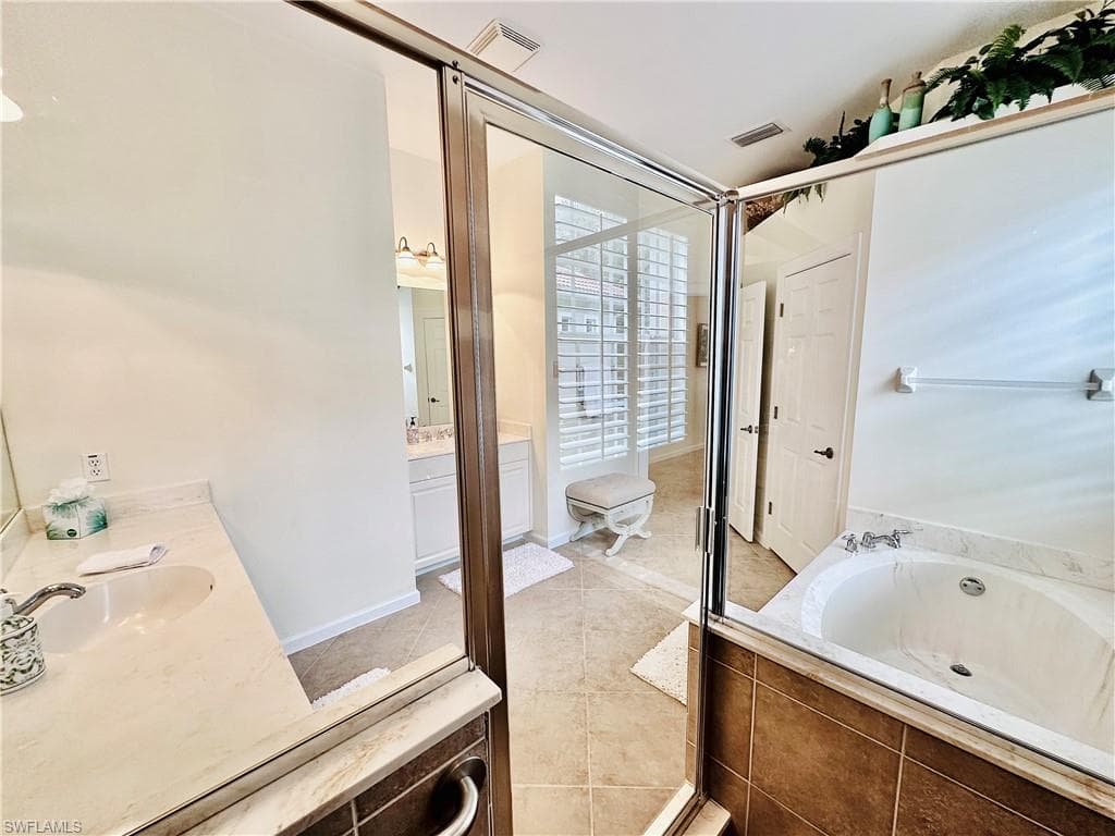 Bathroom featuring vanity, tile patterned floors, and a relaxing tiled tub
