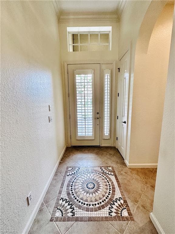 Tiled foyer featuring ornamental molding
