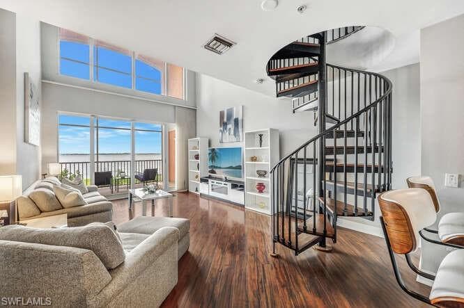 Living room with a high ceiling and dark hardwood / wood-style flooring