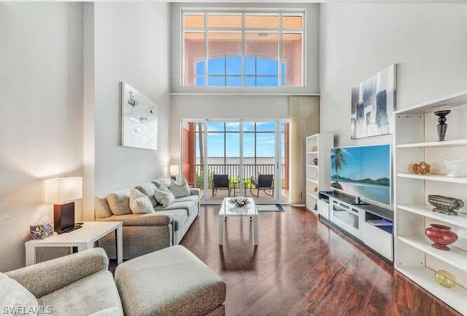 Living room with dark hardwood / wood-style floors and a towering ceiling