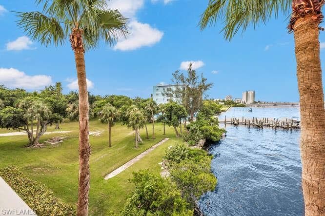 View of community featuring a dock, a lawn, and a water view