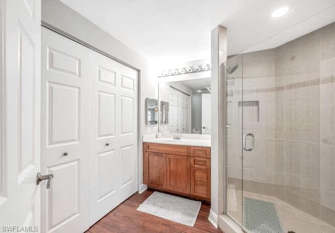 Bathroom featuring an enclosed shower, vanity, and wood-type flooring