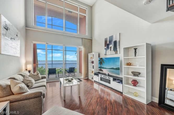 Living room featuring a high ceiling, built in features, and wood-type flooring